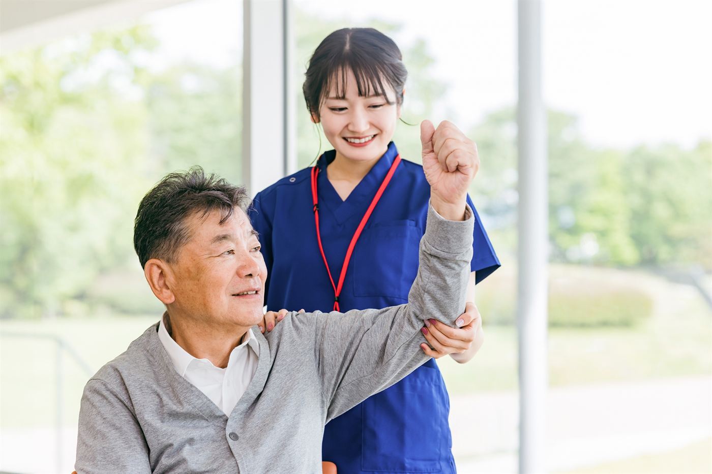 高齢の男性の腕を支えながら運動を指導する理学療法士